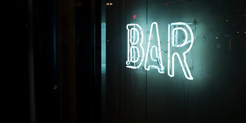 Enseigne « BAR » au néon dans une salle sombre